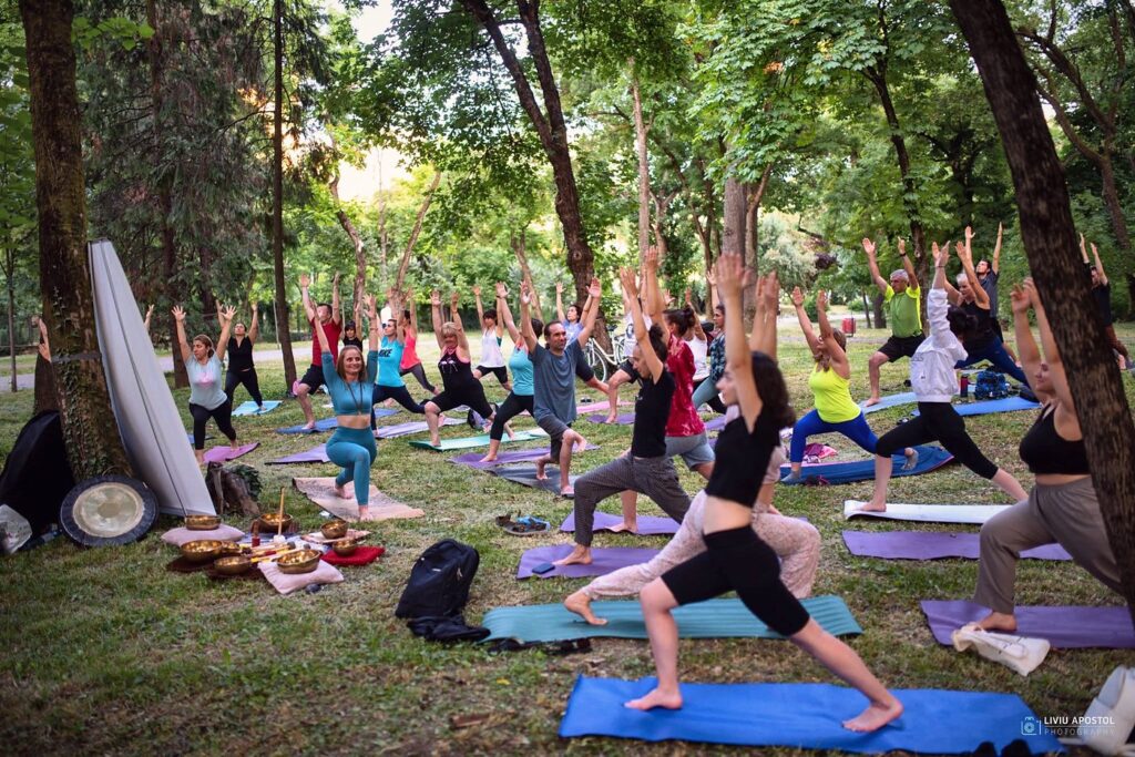 Zeci de oameni fac yoga împreună într-un parc din Timișoara